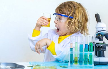 Test tüpleri, reaktörleri ve mikroskobu olan bir çocuğun laboratuvar incelemesi. Seçici odaklanma. çocuk.