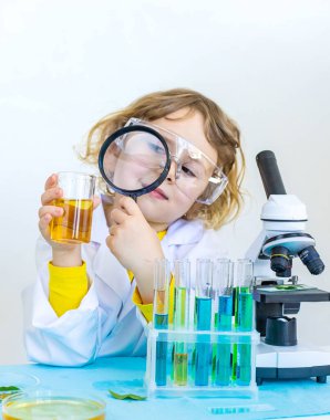 Test tüpleri, reaktörleri ve mikroskobu olan bir çocuğun laboratuvar incelemesi. Seçici odaklanma. çocuk.