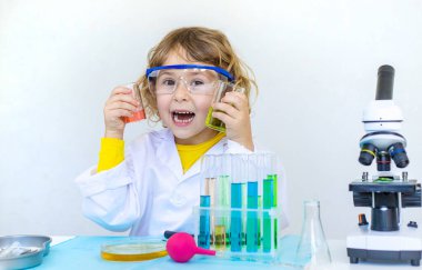 Test tüpleri, reaktörleri ve mikroskobu olan bir çocuğun laboratuvar incelemesi. Seçici odaklanma. çocuk.