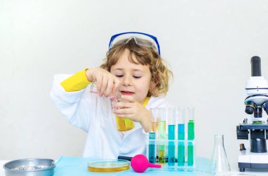 Test tüpleri, reaktörleri ve mikroskobu olan bir çocuğun laboratuvar incelemesi. Seçici odaklanma. çocuk.