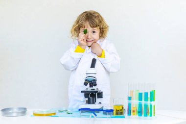 Test tüpleri, reaktörleri ve mikroskobu olan bir çocuğun laboratuvar incelemesi. Seçici odaklanma. çocuk.