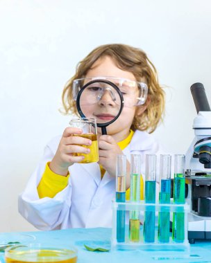 Test tüpleri, reaktörleri ve mikroskobu olan bir çocuğun laboratuvar incelemesi. Seçici odaklanma. çocuk.