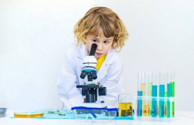 Test tüpleri, reaktörleri ve mikroskobu olan bir çocuğun laboratuvar incelemesi. Seçici odaklanma. çocuk.