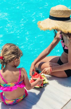 Çocuklar havuzun yanında karpuz yerler. Seçici odaklanma. Yiyecek..