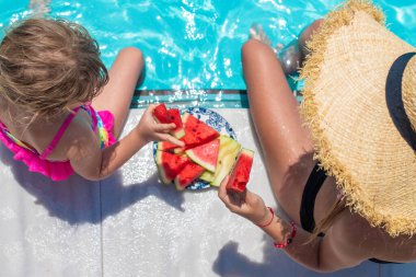 Çocuklar havuzun yanında karpuz yerler. Seçici odaklanma. Yiyecek..