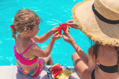 Çocuklar havuzun yanında karpuz yerler. Seçici odaklanma. Yiyecek..