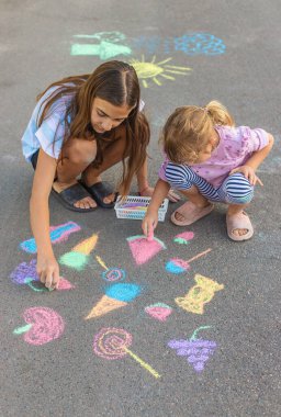 Çocuklar asfalta tebeşirle resim çiziyor. Seçici odaklanma. Çocuk.