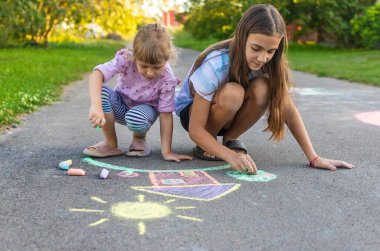 Çocuklar asfalta tebeşirle resim çiziyor. Seçici odaklanma. Çocuk.