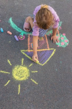 Çocuklar asfalta tebeşirle resim çiziyor. Seçici odaklanma. Çocuk.