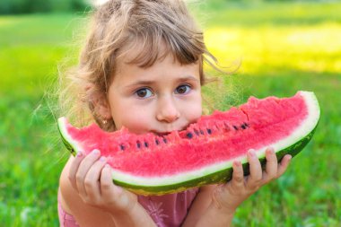 Bir çocuk parkta bir karpuz yiyor. Seçici odaklanma. Çocuk.