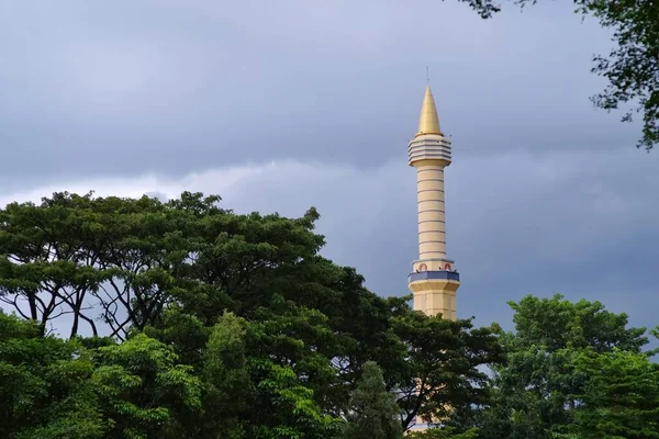 The tower of mosque that rises high among the green trees. Usually used to place loudspeakers to call to prayer notification of prayer times.
