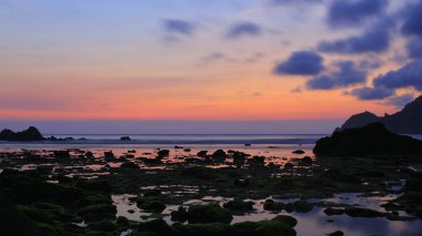 Kıyı şeridinde alacakaranlık, akşam mavi gökyüzü ve kaya bölgesinde yoğun gölgeler..