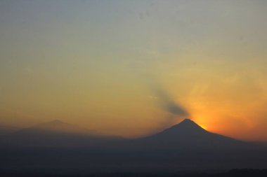 Silhouette of Mount Merapi with a gold sky before sunrise.