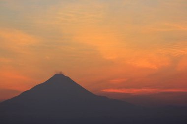 Güneş doğarken kırmızı-turuncu gökyüzü olan Merapi Dağı 'nın silueti. Stratovolcano tipi bir püskürmeye sahip bu volkan Yogyakarta ve Orta Java bölgelerinde yer almaktadır..