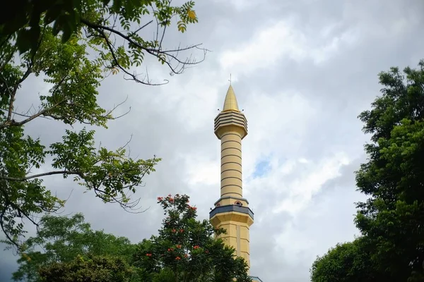 The tower of mosque that rises high among the green trees. Usually used to place loudspeakers to call to prayer notification of prayer times.