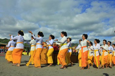 Parangkusumo Beach, Yogyakarta, Indonesia, March 11, 2018. Beautiful Hindu women gracefully move to Rejang dance during celebration of Melasti religious ceremony. clipart