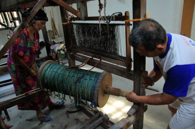 Yogyakarta, Endonezya, 26 Ekim 2015. Yaşlı bir zanaatkar, bir tekstil fabrikasında çalışmaya başlamadan önce geleneksel dokuma tezgahı hazırlıyor..
