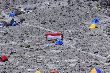 Boyolali, Indonesia, Oct 25, 2014. Climbers spread red and white cloth symbolizing the Indonesian national flag in the sandy field area of Pasar Bubrah, before the peak of Merapi. clipart