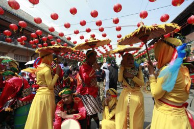 Solo, Endonezya, 11 Şubat 2018. Grebeg Sudiro karnaval katılımcıları sıcak güneşten korunmak için dekoratif şemsiyelerin altına sığınıyor.