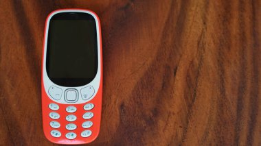 Siyah arkaplanda düğmeleri olan bir tuş takımı telefonu. Siyah ekranlı eski bir cep telefonu. Hindistan 'da 2g, 3g' lık turuncu bir cep telefonu. Teknoloji ve sosyal konsept.