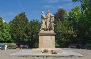 Zilina, Slovakya-26 Mayıs 2022: Şehir parkı, şehrin kurtuluşunun 10. yıldönümü onuruna taş heykel, 25 Mayıs 2022 'de Slovakya' da iki evsiz adam 