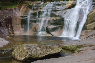 Mumlava şelalesi, ön plandaki granit taşın içinde. Dağ Nehri Mumlava, Krkonose Ulusal Parkı, Çek Cumhuriyeti, yaz öğleden sonra.