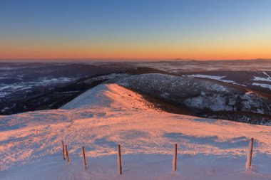 Kış, gün doğumu, Snezka 'dan pembe dağa, krkonose dağına, Çek Cumhuriyeti' ne manzara... Yol boyunca ahşap uzun çubuklar, kış mevsimi için turistik işaretler var.. 