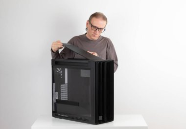 Man installing  top panel with dust filter to  PC case, empty big tower, chassis. Under top panel is place for 420 mm radiator for AIO cooling clipart