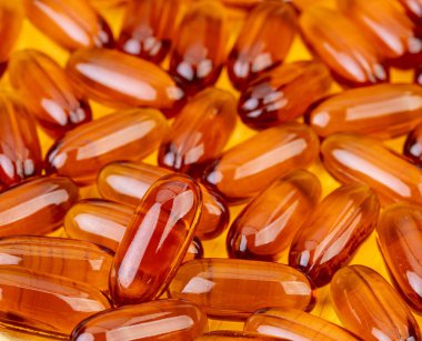 Omega 3 ve tahta arka planda D vitamini içeren balık yağı kapsülleri..