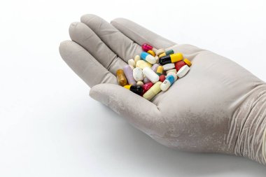 Eczacılık Dizisi: Eldivenli bir el, ilaç, kapsül ve tabletlerden oluşan bir kaleydoskop sunarak, temiz ve klinik bir zemin üzerinde sunulan karmaşık ilaç ve sağlık hizmetleri dünyasını ima ediyor..
