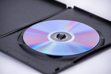 Yansıtıcı yüzeye sahip bir optik disk, kısmen açık olan siyah plastik kutunun içine, beyaz arka plana yerleştirilir. disk renk spektrumunu gösterir