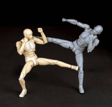 Saldırgan sağdan tekmeliyor. Savunmacı çapraz adım atar, sol koluyla blok yapar, hafifçe eğilir, sonra sol tekme saldırganın destek ayağını tekmeler.