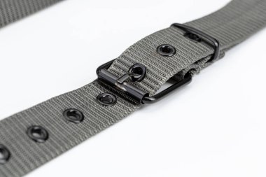 Metal tokalı gri naylon kemer, dayanıklı tasarımını ve birden fazla göz şeklini sergiliyor. Kemer beyaz arkaplan üzerine serilmiş, dokusu ve işlevselliği vurgulanıyor