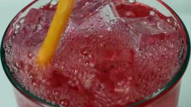 Turuncu saman baloncukları, buz küpleri ve canlı renklerle ferahlatıcı bir kırmızı soda enerji ve içecek deneyimini canlandırır.