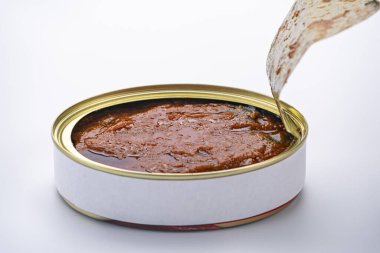 Altın kapaklı, beyaz arka planlı ve açılması zor bir et konservesi açmak..