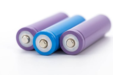 Beyaz zemin üzerine dizilmiş mor ve mavi silindirik şarj edilebilir piller temiz modern enerji depolama teknolojisi güç arzı minimalist canlı renk
