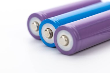 Beyaz zemin üzerinde mor ve mavi şarj edilebilir piller silindirik şekilleri kapatın modern enerji depolama teknolojisi güç kaynağı minimalist stil