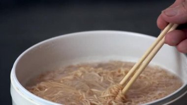 Yemek çubuğu buharı tüten hazır şehriye kaynayan beyaz tencereden iştah açıcı bir sahne yaratır sıcak buhar yükselir, yumuşak dokuya sahip hızlı ve kolay Asya yemeği pişirir, konforlu yemekler ve lezzetli