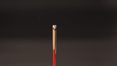 Hafif dumanlı yanan tütsü çubuğu karanlık arka planda yükseliyor, meditasyon, rahatlama, ruhsal dinginlik ve odaklanma için sakin ve huzurlu bir atmosfer yaratıyor.