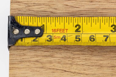 Sarı bir mezura, metal kanca ölçüm ölçeği metrik tahta, atölye marangozluğu diyet doğruluk aracını kapatın.