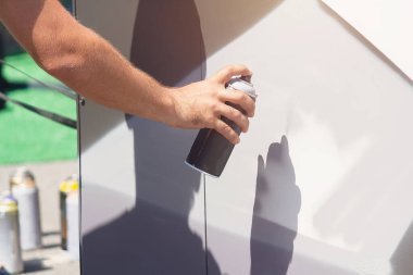 Grafiti yapan, sprey kutusunu elle tutan bir adam. Grafiti için sprey sprey boya. Sokak sanatçısı duvara grafiti yapıyor.