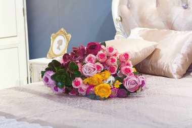 Zarif bir yatak odasında, yatağın üzerinde güzel bir buket gül.