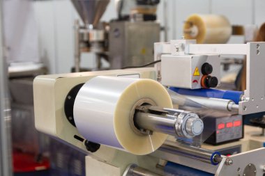 Yiyecek ambalajı ya da plastik ambalaj poşeti üretimi için bir paket taşıyıcının üzerinde bir rulo plastik film. Polietilen film rulodan makineye aktarılıyor. Gıda endüstrisi