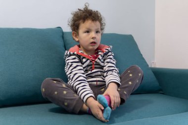 Odadaki kanepede oturan tatlı kıvırcık bebeğin portresi. İnsanlar