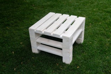 Çimlere sade ahşap bir tabure. Rahatla.