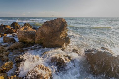 Dalgalar deniz kıyısında taşların üzerinde akıyor. Kırım