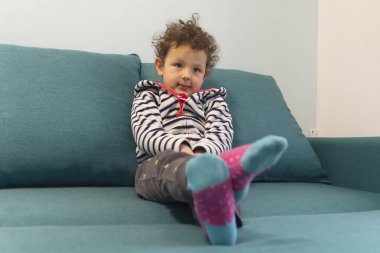 Odadaki kanepede oturan tatlı kıvırcık bebeğin portresi. İnsanlar