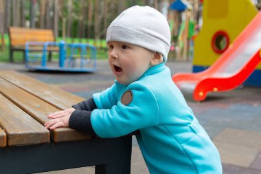 Çocuk serin havada parktaki oyun alanında oynar. İnsanlar