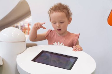 Çocuk bir oyun alanında eğitici bir uygulamayla meşgul oluyor. İnsanlar