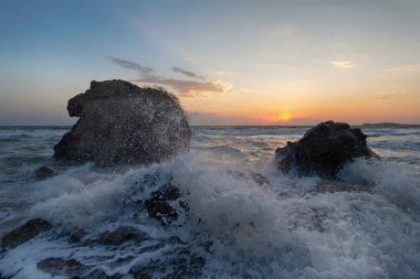 Gün batımında dalgalar plajda kayalara vuruyor. Kırım